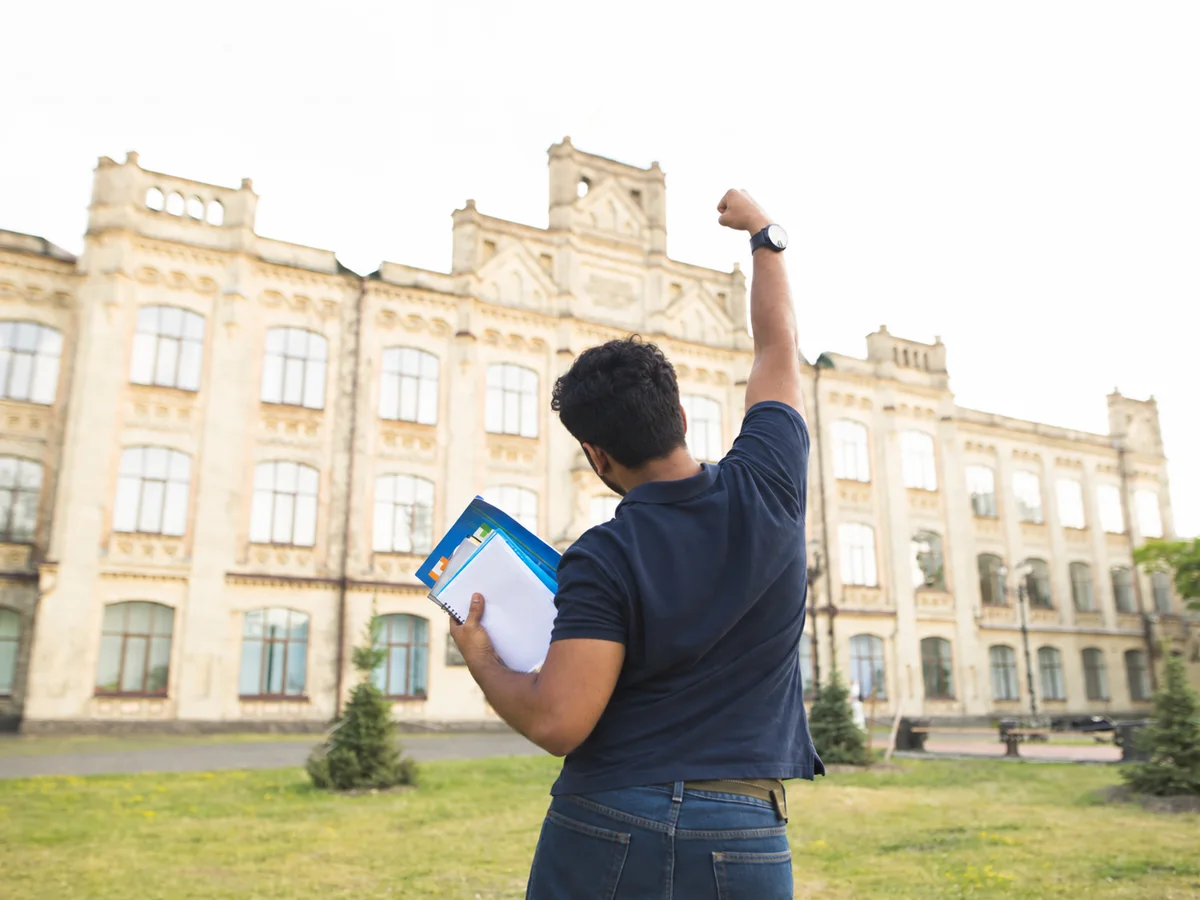 An Indian student in front of a historic university building